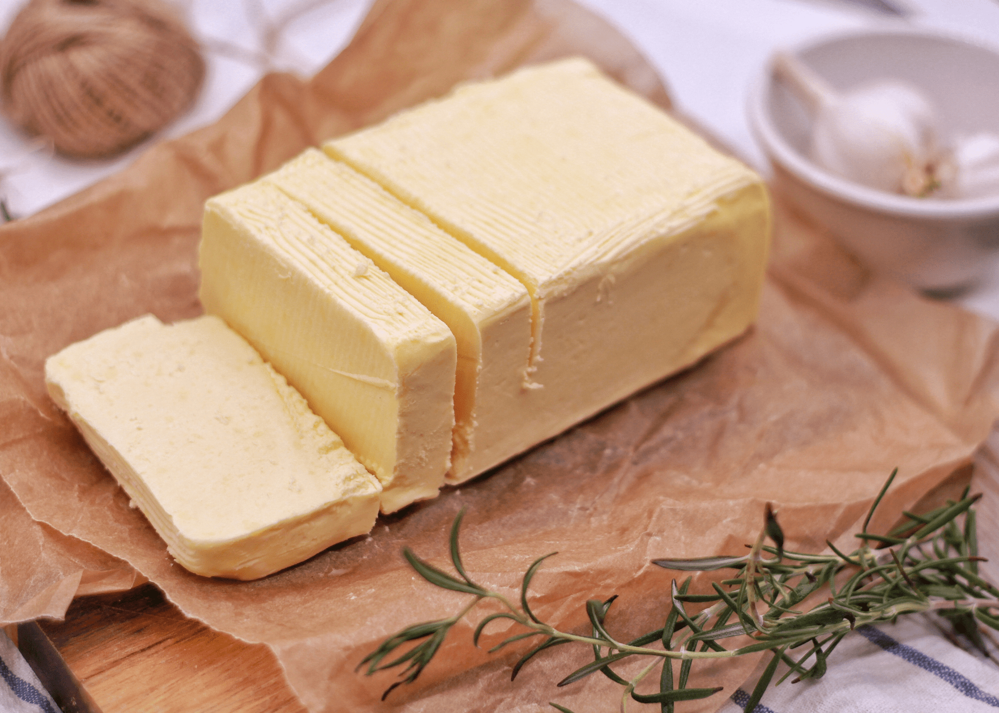 Block of butter on a wooden board with rosemary